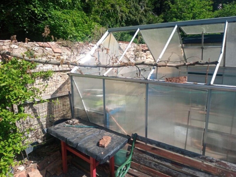 Damage to an allotment holder's greenhouse due to logs and bricks being thrown at it.