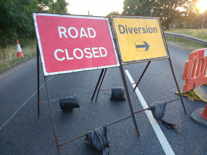 Image of temporary red 'road closed' road sign and yellow 'diversion' with arrow road sign
