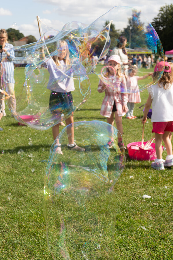 Children having fund outdoors blowing giant bubbles